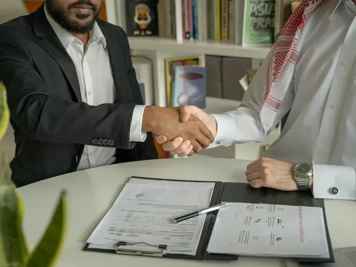 Two professionals shake hands over a clipboard and contract paperwork, illustrating trusted partnerships in city services